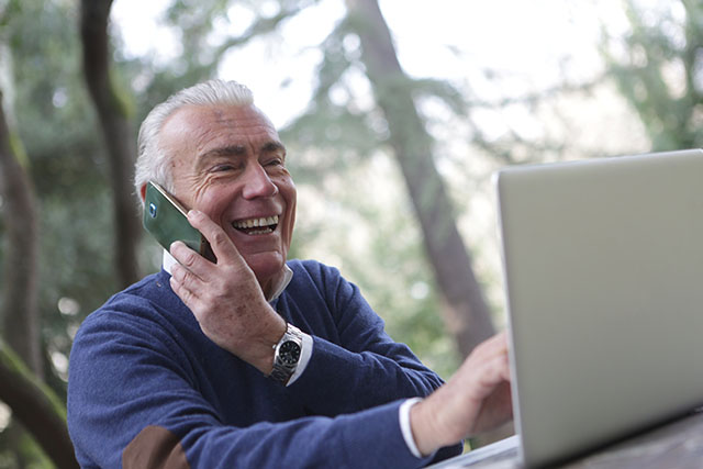 an elderly booking a free consultation for dental implants, and filling up new patient information on a laptop