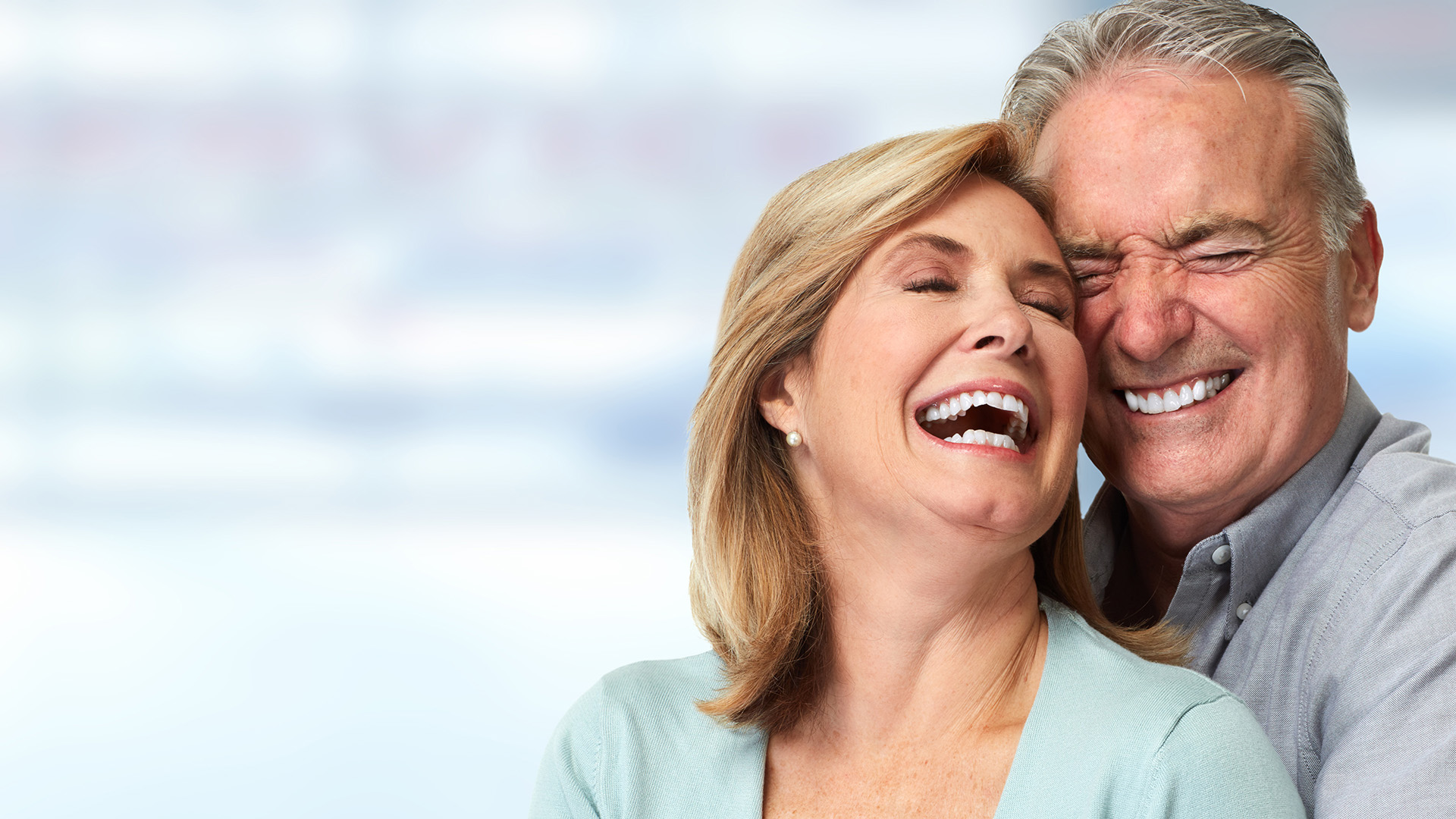 an elderly couple smiling after getting denture implants in modesto through us